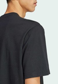 Sort bomuld T-shirt med rund halsudskæring og korte ærmer, med en glat tekstur og minimalistisk design.
