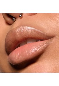 Nærbillede af fyldige læber med en gradient finish fra lys nude til bronze, med en blank overflade og en ansigtspiercing over den øverste læbe.