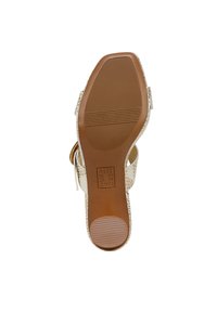 Lichtbruine sandaal met een getextureerde, geperforeerde bovenkant in beige. Heeft een rubberen zool met horizontale groeven voor grip. Te verstellen met een gesp.