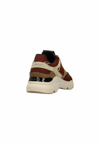 Sportieve sneakers met een mix van rood, bruin en crèmekleurig suede, voorzien van een dikke witte zool en zwarte accenten bij de hak. Textuuraccenten zijn zichtbaar.
