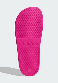 Adidas bright pink sandal sole features a textured diamond pattern and embossed logo, designed for grip and stability.