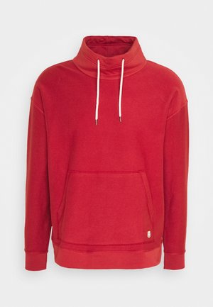 Sweatshirt rouge à col haut, avec cordons de serrage et poche avant. Présente des poignets côtelés et un tissu texturé. Détail de petit logo.