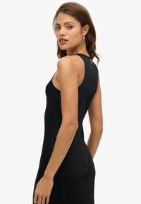 Robe noire sans manches avec une silhouette ajustée et un léger éclat, présentant un col haut et un discret détail à l'arrière.