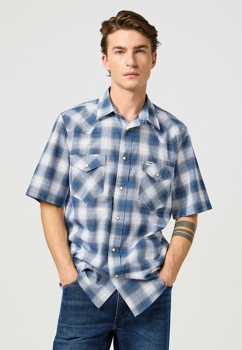 Lyhythihainen ruudullinen shirt, jossa on sinisen ja valkoisen sävyjä, kaksi rintataskua, helmi-napitus ja rento istuvuus.