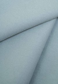 Textured fabric in light blue, showcasing a smooth surface and subtle weave pattern, folded to reveal multiple layers and depth.