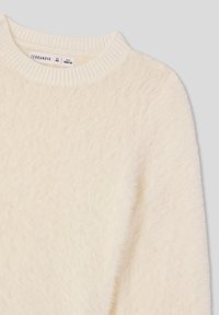 Biały, puszysty sweter z okrągłym, prążkowanym dekoltem i miękką teksturą. Metka informuje "Terranova". Brak widocznych wzorów lub elementów metalowych.