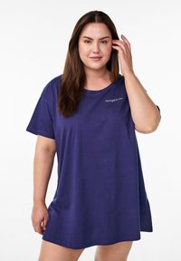 Överdimensionerad t-shirtklänning i marinblå färg gjord av mjukt tyg. Har korta ärmar och rund halsringning. Diskret broderad detalj på bröstet.