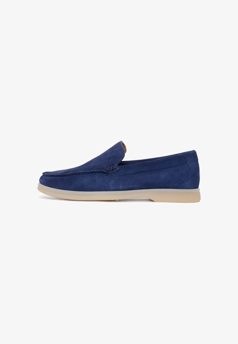 Scarpe slip-on in suede blu navy con una finitura liscia, caratterizzate da un dettaglio cucito lungo la parte anteriore e una suola in gomma di un tenue color nocciola.