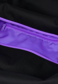 Schwarzes Stoffinterieur mit einer lila Reißverschlusstasche. Der Reißverschluss hat ein passendes lila Band, das die auffällige Farbe der Tasche betont.