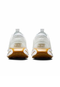 Bijele Nike tenisice s teksturiranim gornjim dijelom, s zlatnim logotipom i potplatom od gumene gume. Minimalistički dizajn sa trakicom za povlačenje.