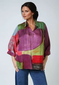 Farbenfrohe Seidenbluse mit lockerer Passform. Sie weist verschiedene Schattierungen von Purple, Grün, Rot und Blau in abstrakten Mustern auf. Klassischer Kragen und hochgekrempelte Ärmel.