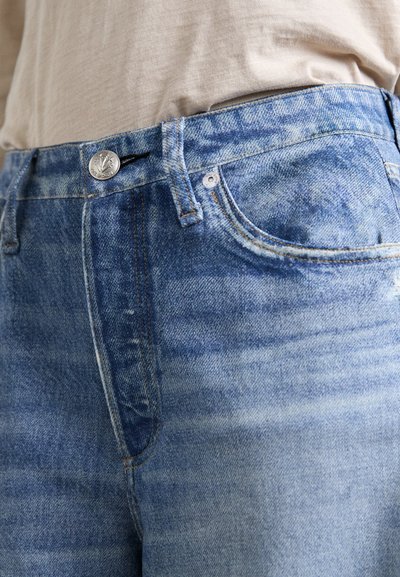 Light blue denim jeans feature a classic five-pocket design, a silver button at the waist, and subtle fading along the fabric texture.