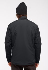 Zwarte geïsoleerde jas met een gestroomlijnd ontwerp en een hoge kraag. Kenmerkt zich door een zachte, gladde textuur en eenvoudige, minimalistische stikseldetails.