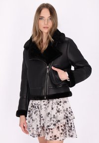 Zwarte faux leren cropped jas met een zachte, zwarte leren kraag en manchetten. Voorzien van een rits aan de voorkant en een zijzak.