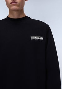 Black sweatshirt with a round neckline and long sleeves. Features a white printed logo on the left chest. Made of soft, textured material.
