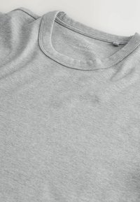 Tissu gris clair à côtes avec un col rond, montrant une partie d'un devant de chemise plié et la zone de l'épaule.