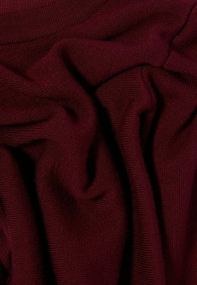 Tessuto a maglia bordeaux con una trama liscia, che mostra pieghe e grinze, evidenziando il suo aspetto morbido e accogliente.