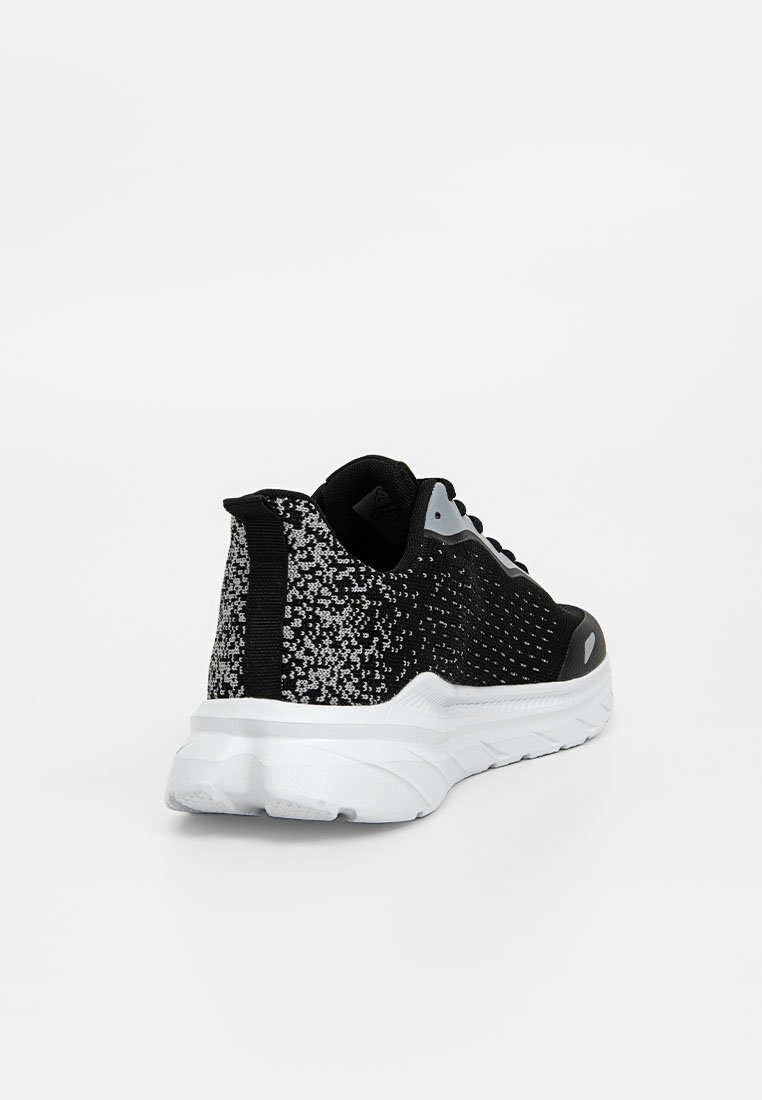Baskets tricotées noires et grises avec une épaisse semelle blanche, un tirant noir au talon et des lacets, angulées pour montrer l'arrière et le côté.