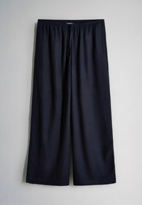 Losse zwarte broek met trekkoord, brede pijpen en elastische tailleband, afgebeeld tegen een effen lichte achtergrond.