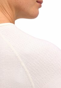 Garment bianco con trama, dal design aderente, caratterizzato da sottili motivi orizzontali e dettagli di cucitura a contrasto lungo le spalle.