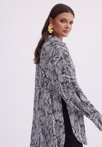 Czarny i biały kimono w stylu topu z luźnym krojem, długimi rękawami i lekkim materiałem o teksturowanym wyglądzie.