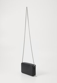 Black faux leather crossbody bag with a textured finish, rectangular shape, silver chain strap, and zip closure.