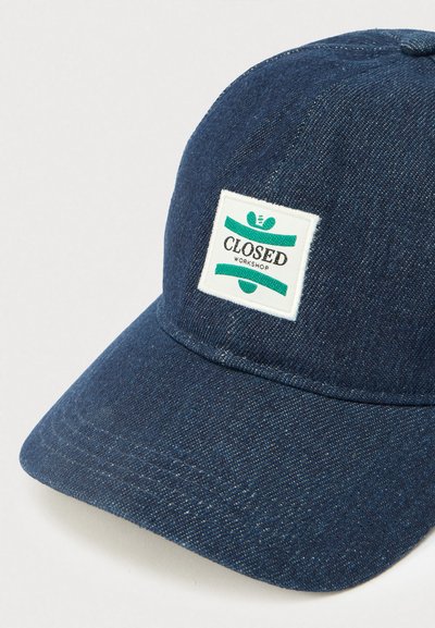 Σκούφος μπέιζμπολ από σκούρο μπλε τζιν με λευκή τετράγωνη ραφή που εμφανίζει πράσινες ρίγες και το κείμενο «CLOSED WORKSHOP».