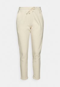 Pantalones de chándal color crema hechos de una tela suave. Cuentan con una cinturilla elástica con cordón y piernas ajustadas con puños de canalé.