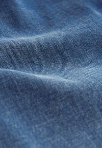 Denim stof in een diepe blauwe kleur, met een gladde textuur en lichte variaties in schaduw, en een klassiek twill-weefpatroon.
