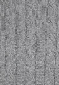 Tissu gris tricoté avec un motif torsadé, présentant des dessins en relief torsadés s’étendant verticalement, créant un aspect texturé et chaleureux.