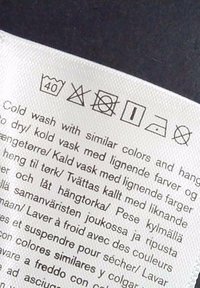 Étiquette de soin du linge indiquant les symboles pour lavage à 40°C, pas d’eau de Javel, ne pas sécher en machine, suspendre pour sécher, repasser à basse température et pas de nettoyage à sec.
