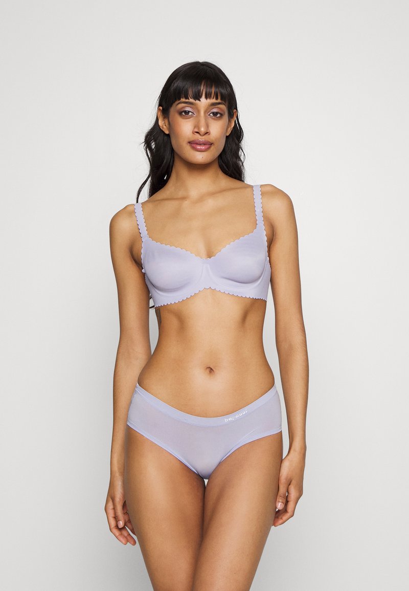 Intimo di colore lavanda chiaro con bordi scallop. Il reggiseno presenta coppe strutturate e le mutandine hanno una texture morbida e trasparente.