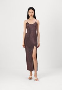 Robe maxi en tissu métallique texturé et foncé, avec de fines bretelles et une fente sur le côté. Les bretelles spaghetti et la silhouette ajustée mettent en valeur le design.