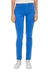 Strakke spijkerbroek van rekbare blauwe denimstof, met vijf zakken, een knoop aan de voorkant en een gladde textuur. Draag met witte sneakers.