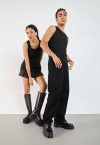 Black ribbed tank tops, a short black skirt with frayed hem, and black platform boots. Both figures wear black pants and shoes with yellow accents.