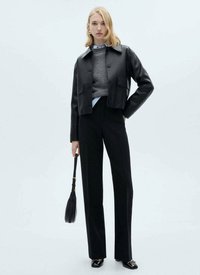 Black cropped leather jacket over a gray sweater and blue shirt, paired with high-waisted black trousers and black shoes. Small handbag included.