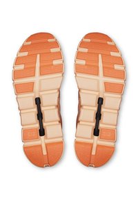 Chaussures de course avec une semelle extérieure orange et crème, présentant des rainures texturées et une pièce centrale noire marquée "SPEEDBOARD."