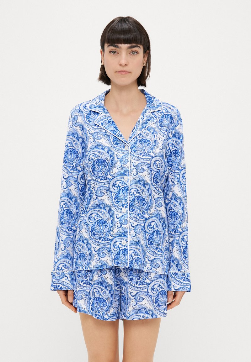 Blue and white patterned pajama set featuring a long-sleeve button-up top and matching shorts, made from lightweight fabric with a smooth texture.