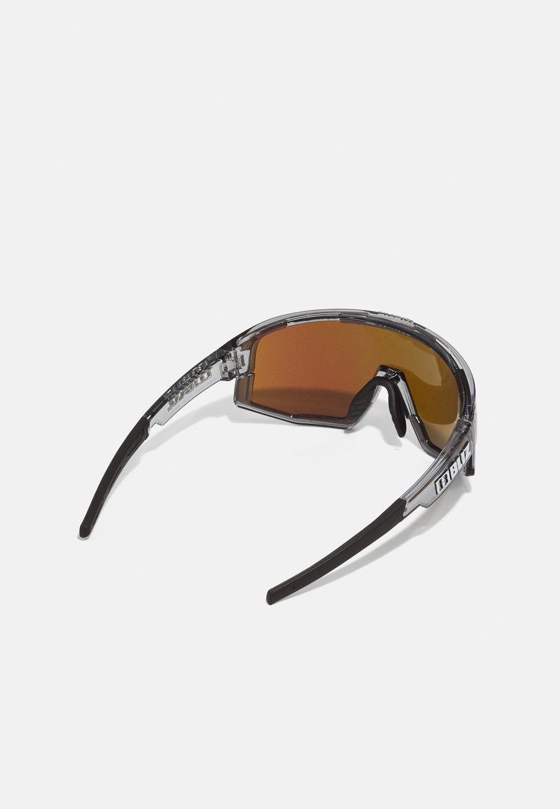 Sonnenbrille mit einem klaren Kunststoffrahmen, braun getönten Gläsern und schwarzen Bügeln. Auffälliges Logo-Detail an der Seite. Schlanker, aerodynamischer Shape.