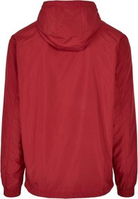 Červená bunda s kapucí, hladká a lehká textura; elastické manžety; navržena s jednoduchou, nezdobenou zadní částí.