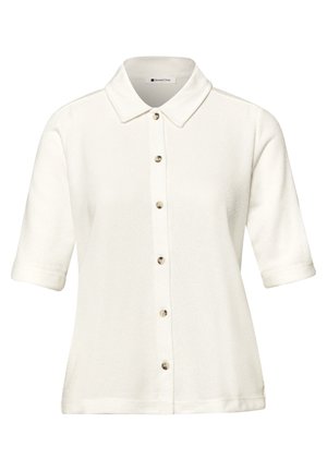 Chemise blanche à manches courtes avec col pointu et six boutons sur le devant.