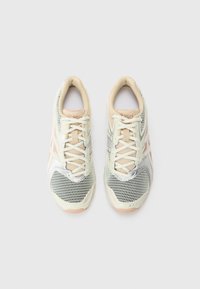 Paar hellbeige und weiße Laufschuhe mit Mesh-Design und Schnürsenkeln, von oben auf einem schlichten weißen Hintergrund gesehen.
