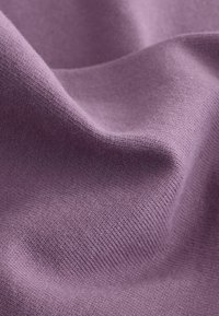 Soft, textured fabric in a muted lavender color, displaying a smooth surface with subtle ribbed patterns and gentle draping.