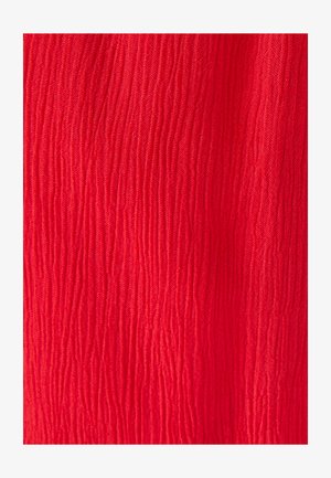 Rode stof met verticale golvende textuurlijnen die een licht verhoogd patroon over het oppervlak creëren.