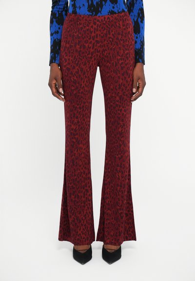 Red leopard print flared pants made of a soft fabric, featuring a snug waistband and extending outward from the knees, paired with black heels.