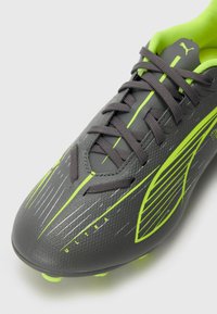 Gray soccer cleat with a textured surface, bright green accents, and thin, dark laces. Features aerodynamic lines and a reinforced toe cap.