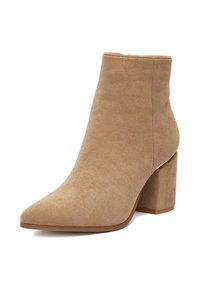 Béžová semišová členková čižma so špicatou špičkou a hrubým podpätkom. Hladká textúra a čistý dizajn, s mierne zúženou časťou okolo členka.