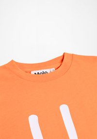 Camiseta de cuello redondo naranja con rayas verticales blancas y una etiqueta de la marca "Molo" visible en el interior del cuello.