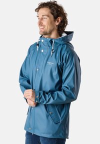 Vattentät blå jacka med huva, tryckknappar och dragsnöre. Har en slät yta och två sidofickor.