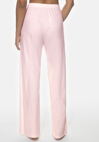 Ljusrosa vida byxor med vertikala ränder, elastisk midja och mjuk textur. Tyget faller mjukt runt benen.